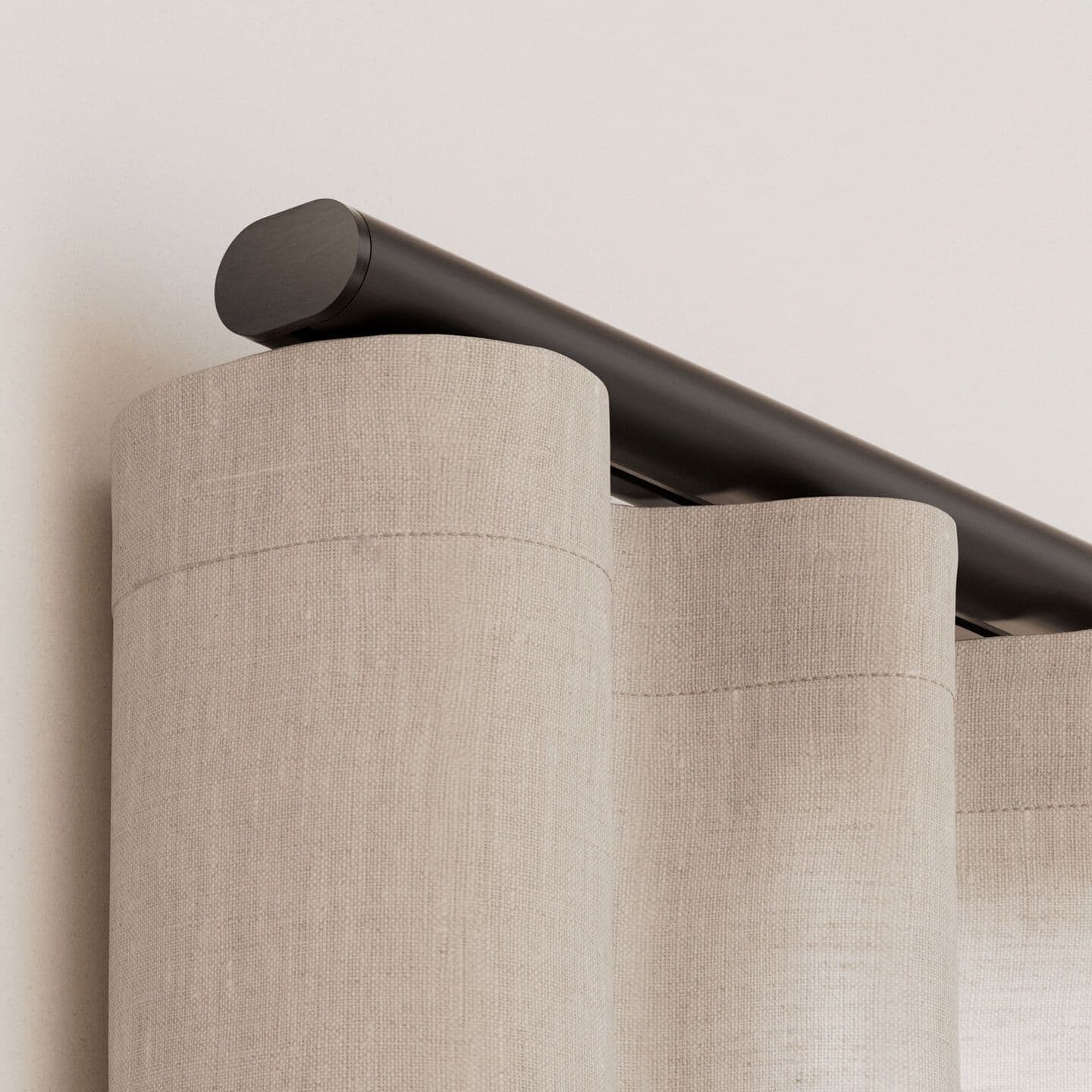 Close-up of a dark bronze drapery track end over linen ripple-fold drapery
