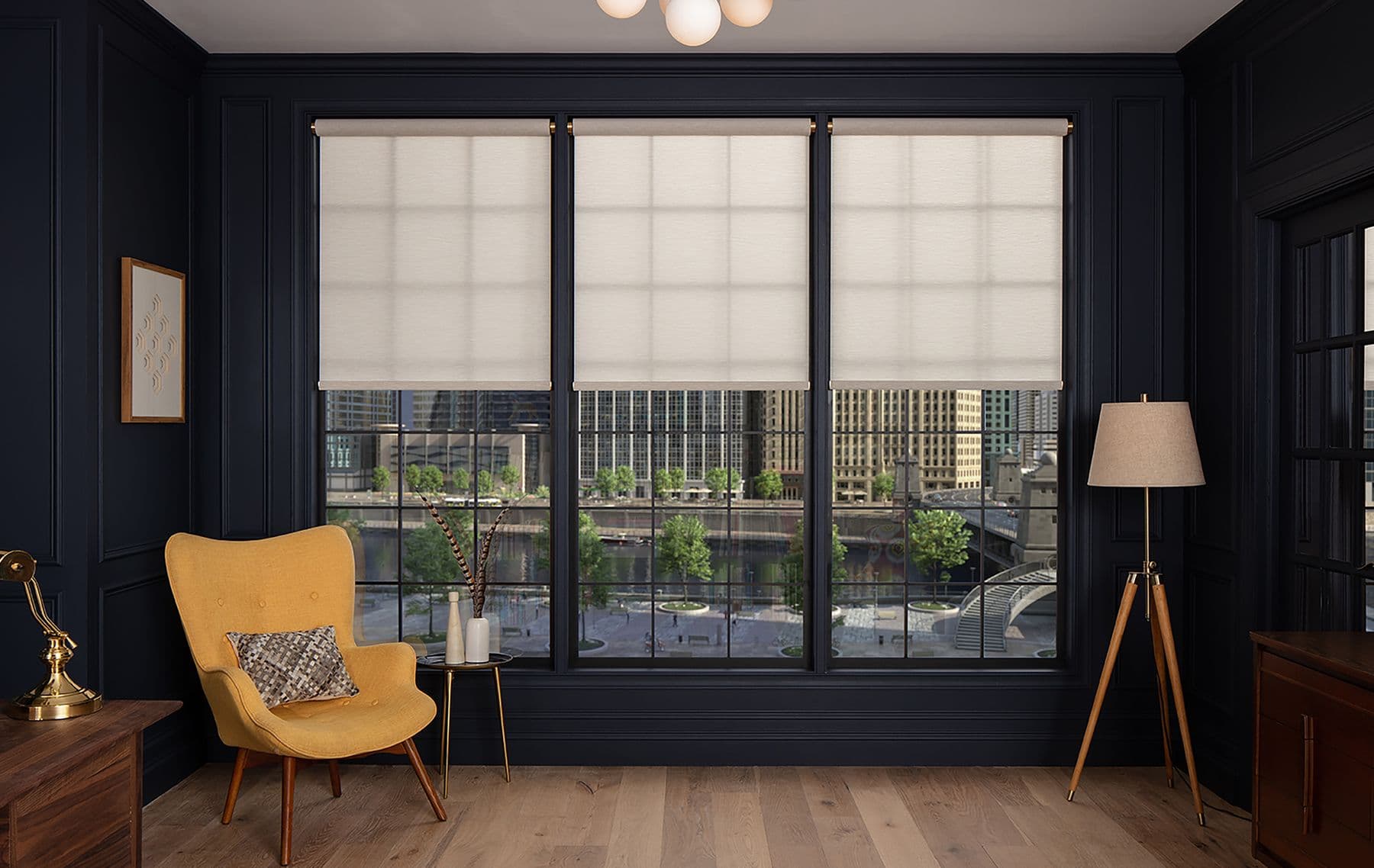 A navy study with three open roll shades on brass brackets, half lowered over a city view