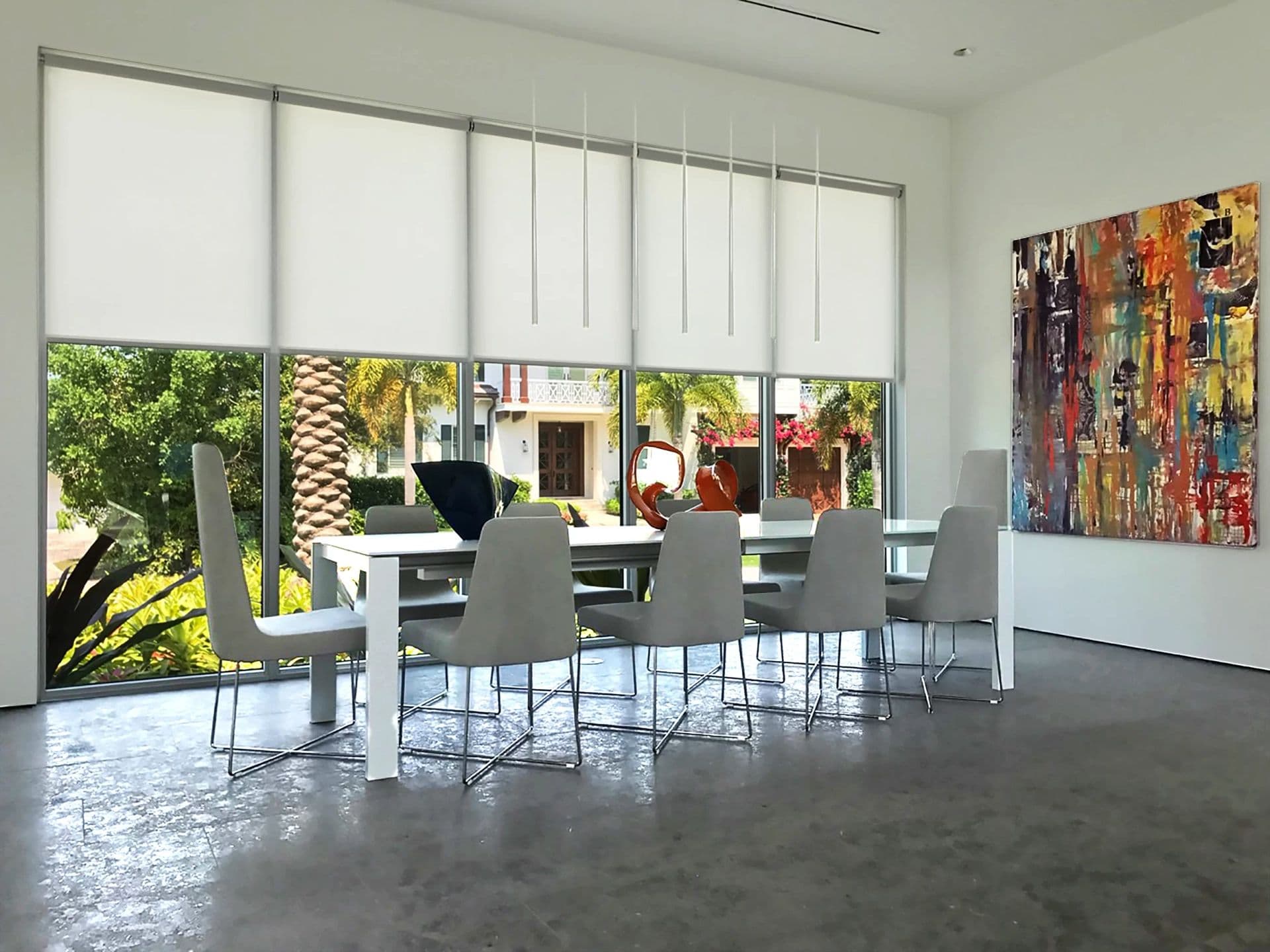 A modern white dining room with translucent shades half lowered over tall glass