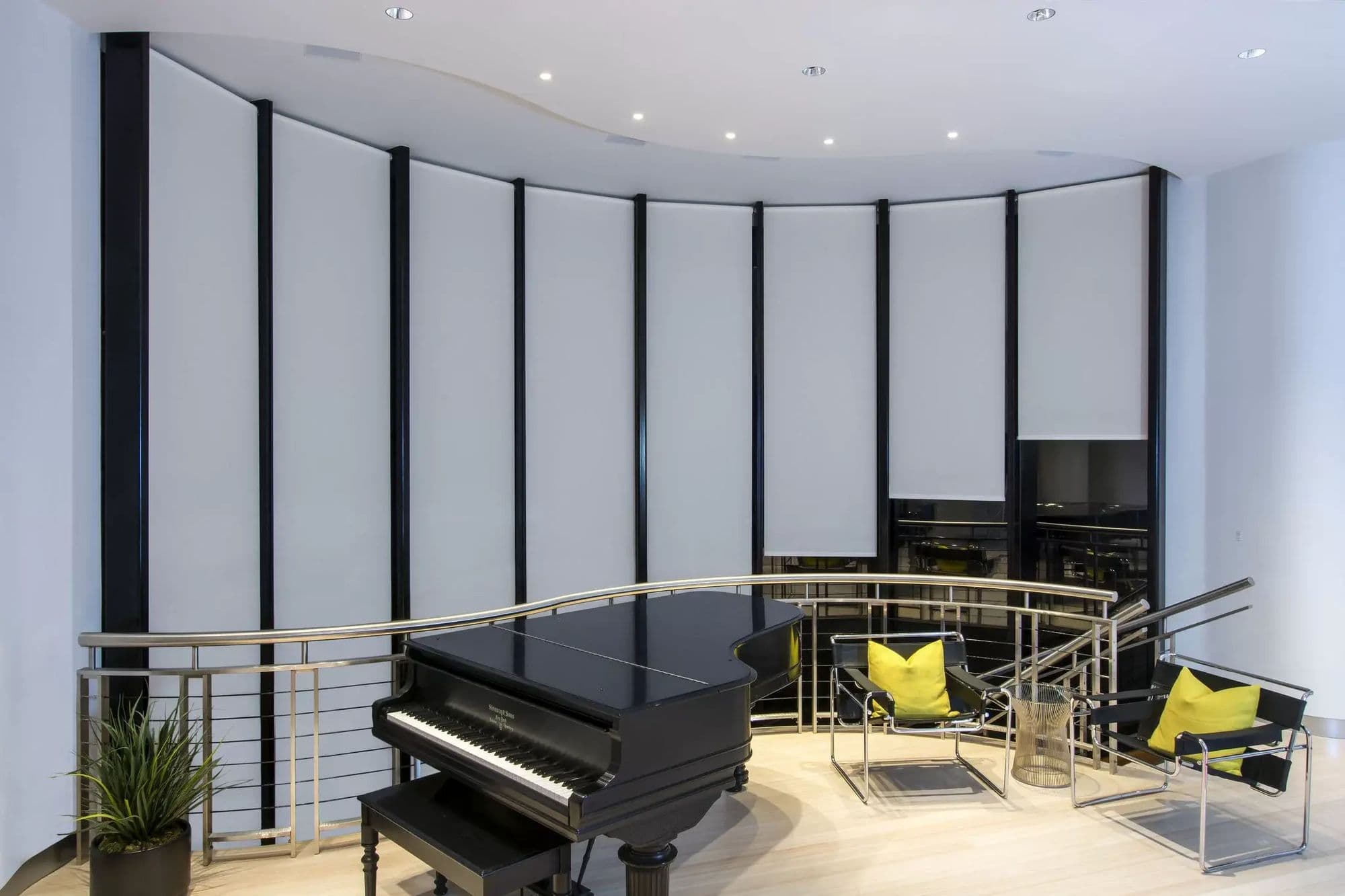 A curved window wall with one white shade per pane, each dropping from a curved ceiling pocket