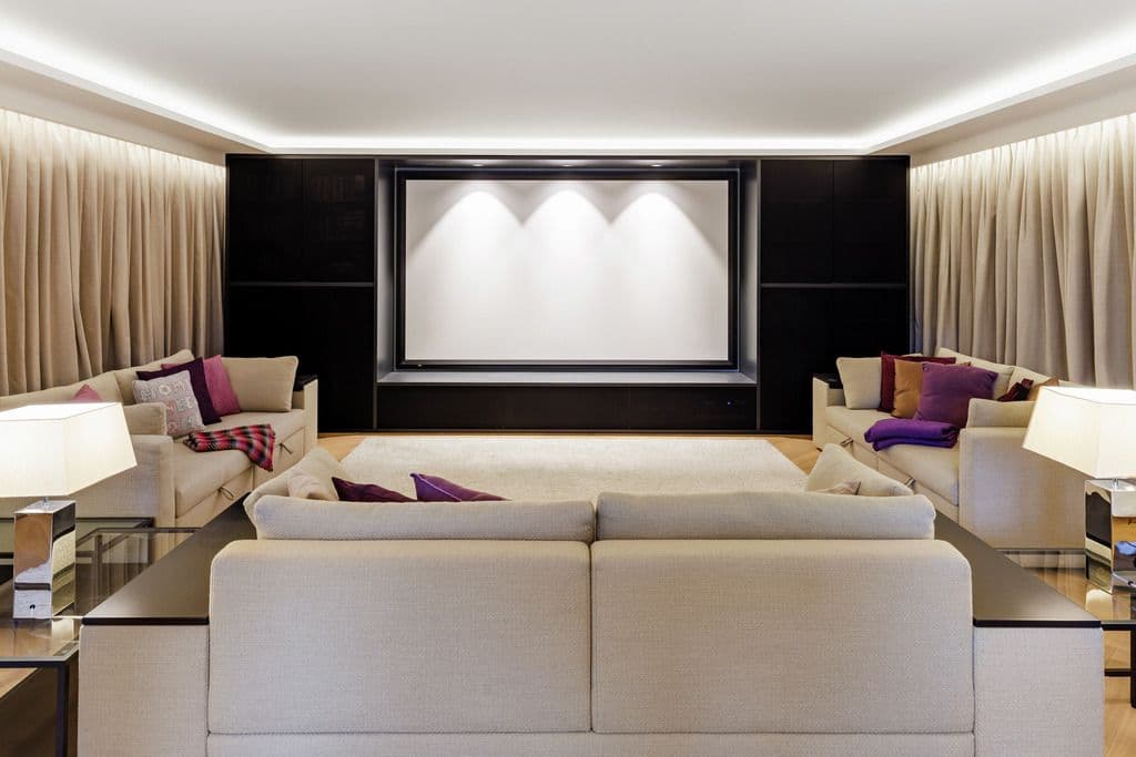 A home theater lined with full-height curtains on motorized tracks